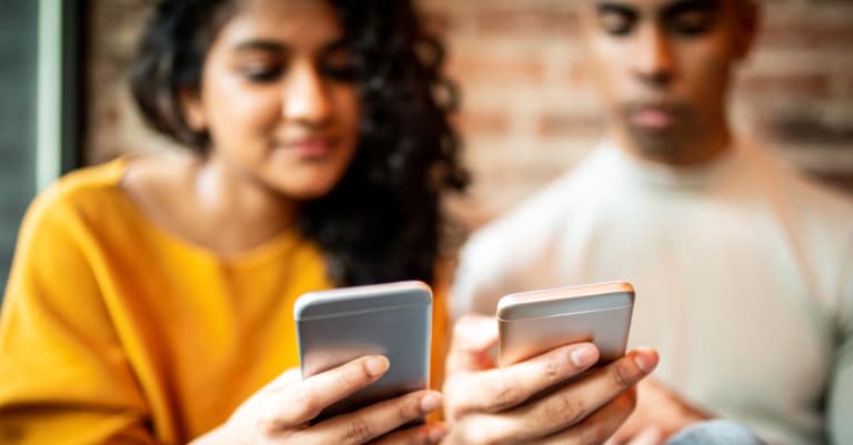 A man and woman looking at their mobile phones